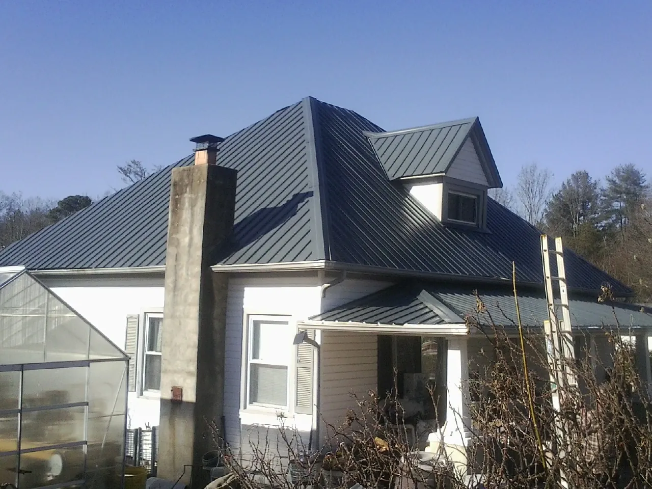 Dark blue standing seam metal roof on a white farmhouse with dormer — Slate & Tile Roof Repair by Roofing Brothers in New Lenox