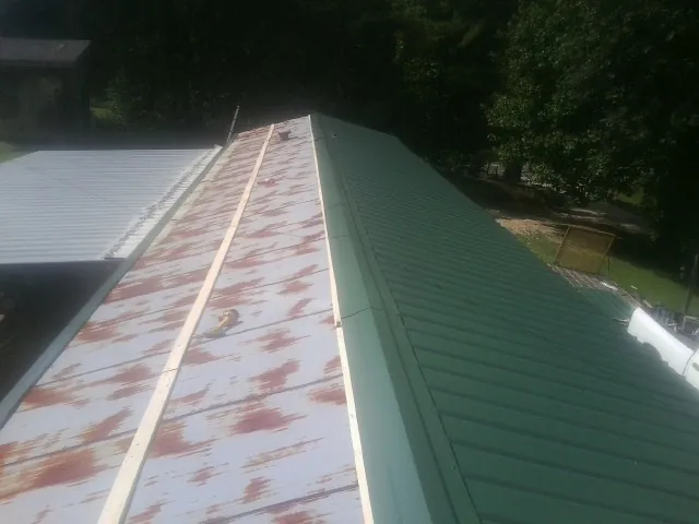 Old rusted panels beside newly installed green metal roofing — Wind Damage Roof Repair by Roofing Brothers in New Lenox