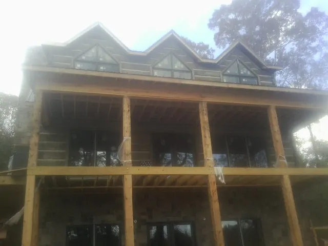 Dormers and porch framing on a large log home under construction — Roof Coating work by our crew in New Lenox