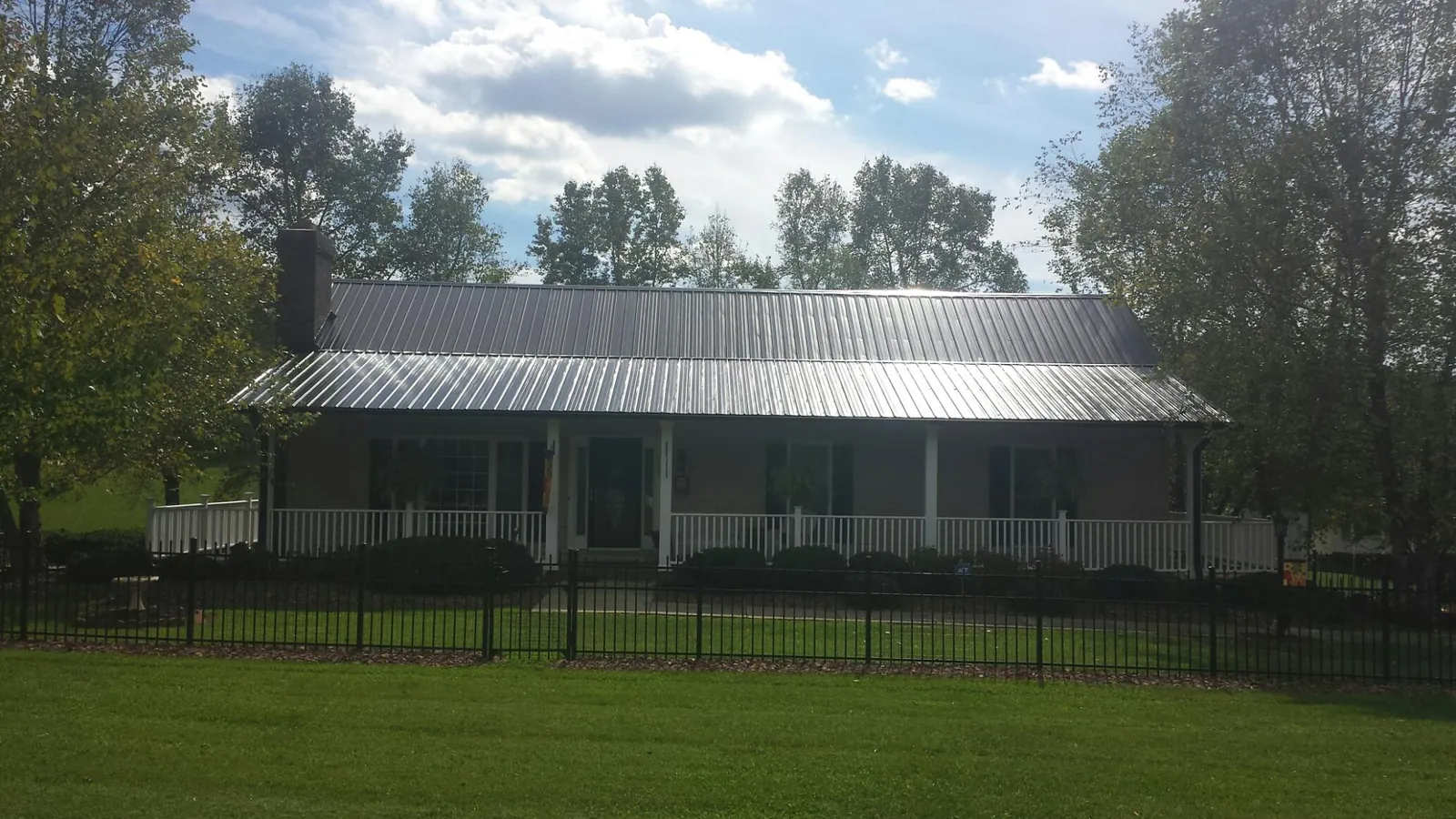Gray metal roof on a brick ranch with a full width front porch — Gutter Guard Installation work by our crew in New Lenox