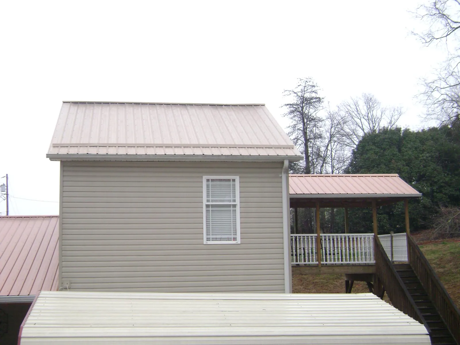 Tan metal roofs on a two story addition and attached porch, from a Roof Replacement job in New Lenox