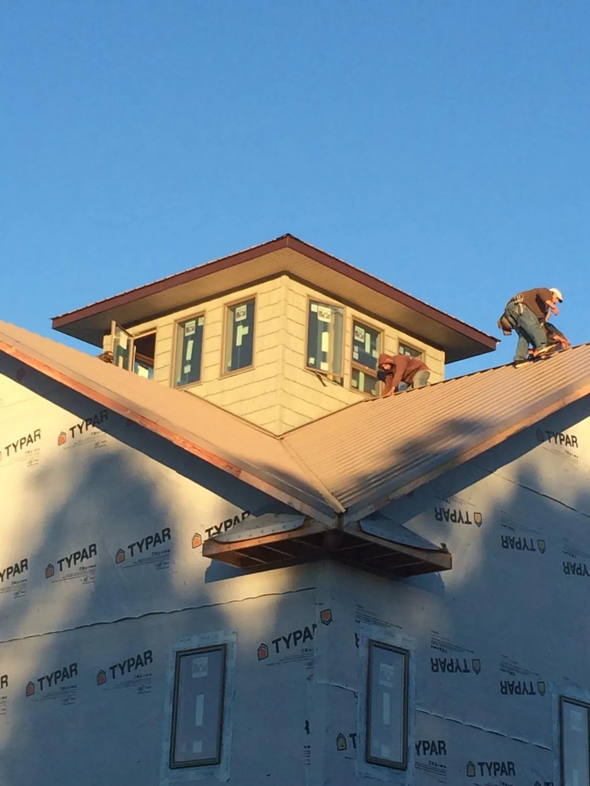Roofers working around a rooftop cupola on a new metal roof at sunset — Roof Waterproofing in New Lenox by Roofing Brothers